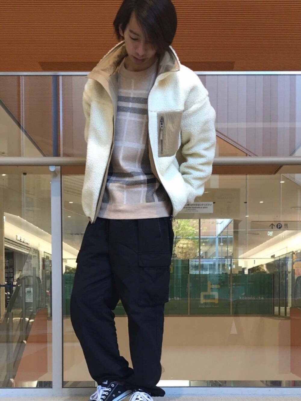 ホワイト系のブルゾン、イエロー系のニット/セーター、ブラック系のカーゴパンツを着用したメンズの冬コーディネートの1枚目の写真