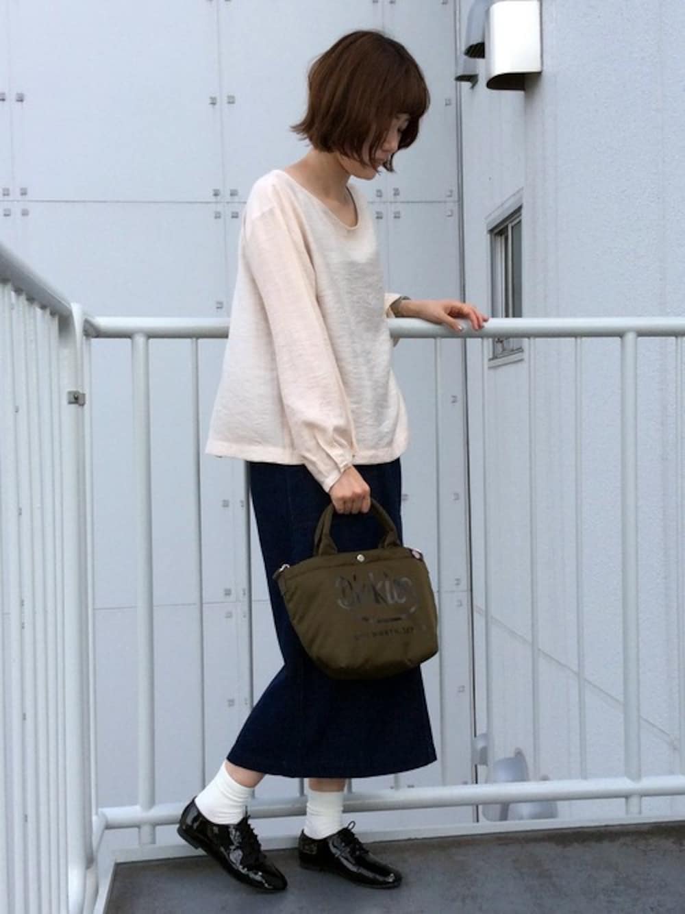 グリーン系のトートバッグ、ホワイト系のシャツ/ブラウス、ブルー系のデニムスカートを着用したレディースの秋コーディネートの1枚目の写真