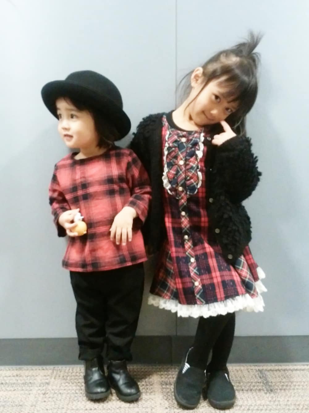レッド系のワンピース、ブラック系のスラックス、ブラック系のニット/セーターを着用したキッズの冬コーディネートの1枚目の写真