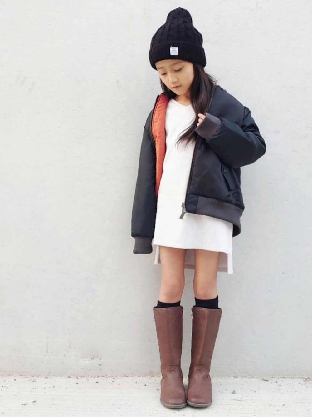 ホワイト系のワンピース、ブラック系のMA-1、ブラウン系のスニーカーを着用したキッズの冬コーディネートの1枚目の写真