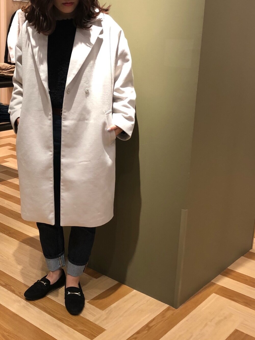 グレー系のダウンジャケット/コート、ブラック系のパンプス、ブルー系のニット/セーターを着用したレディースの秋コーディネートの1枚目の写真