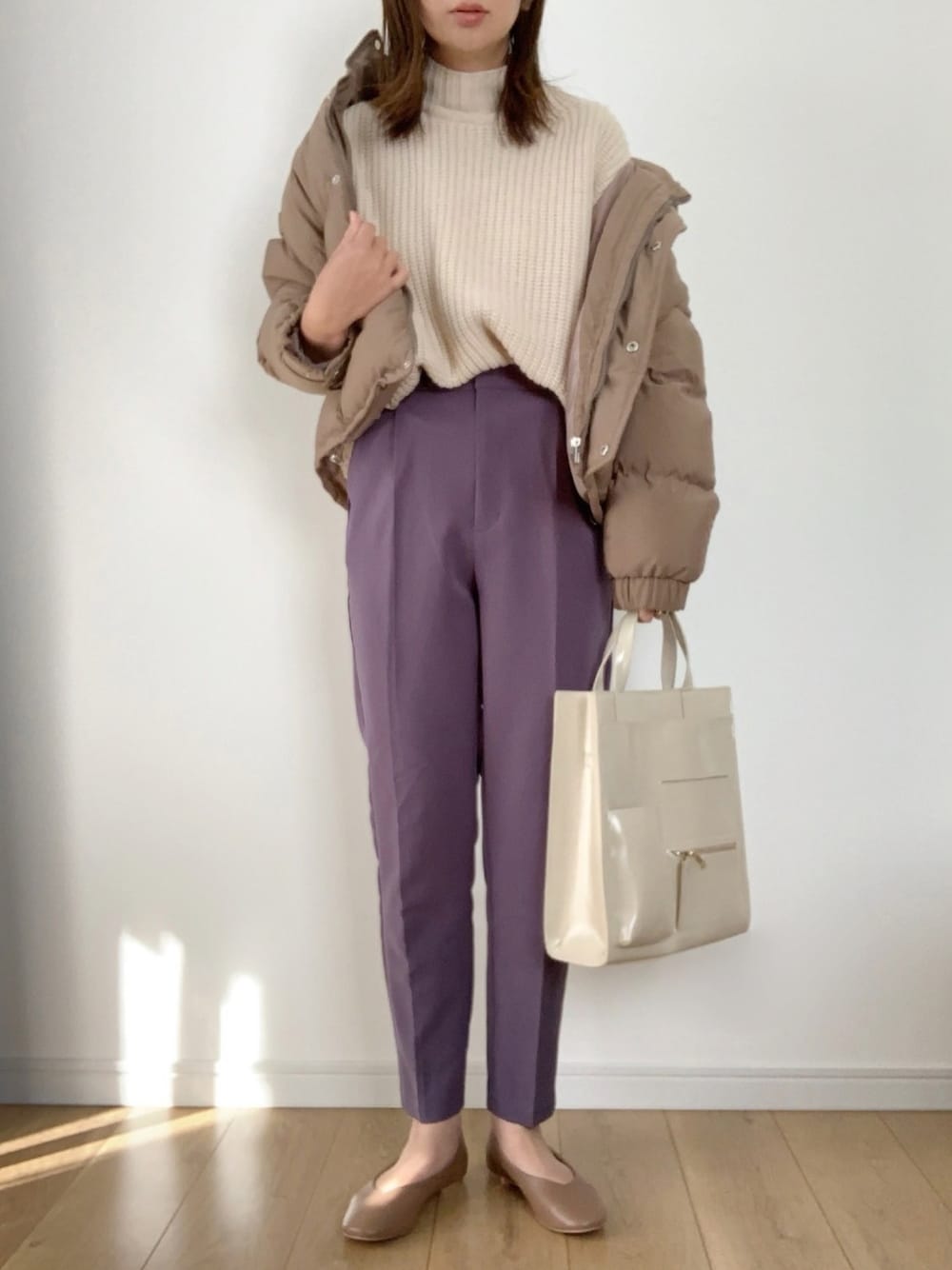 ブラウン系のダウンジャケット/コート、ホワイト系のニット/セーター、ブルー系のパンツを着用したレディースの冬コーディネートの1枚目の写真