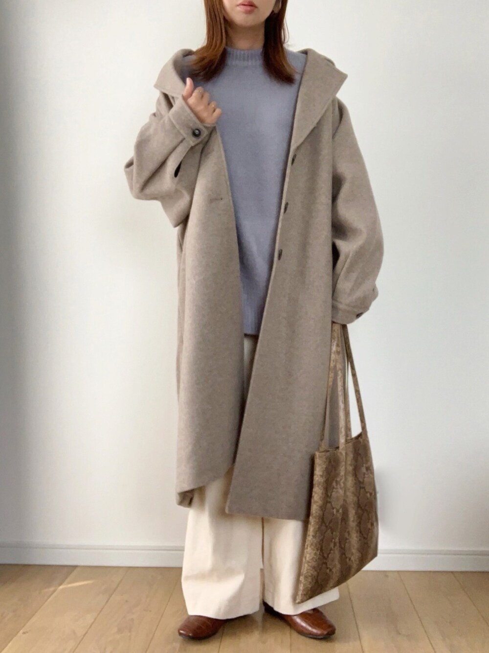 ベージュ系のステンカラーコート、ブルー系のニット/セーター、ホワイト系のその他パンツを着用したレディースの冬コーディネートの1枚目の写真