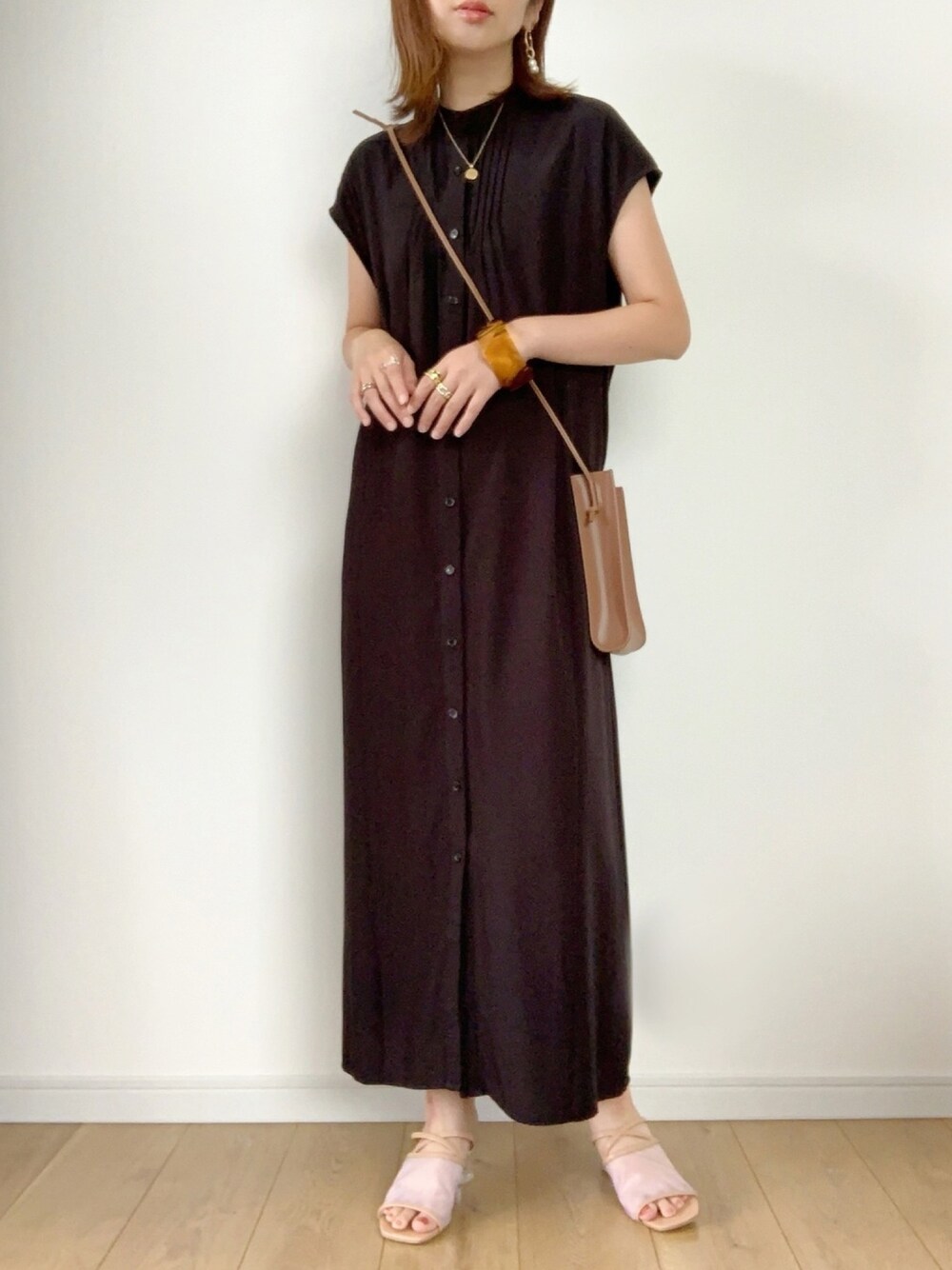 ブラック系のワンピース、ベージュ系のサンダル、イエロー系のハンドバッグを着用したレディースの夏コーディネートの1枚目の写真