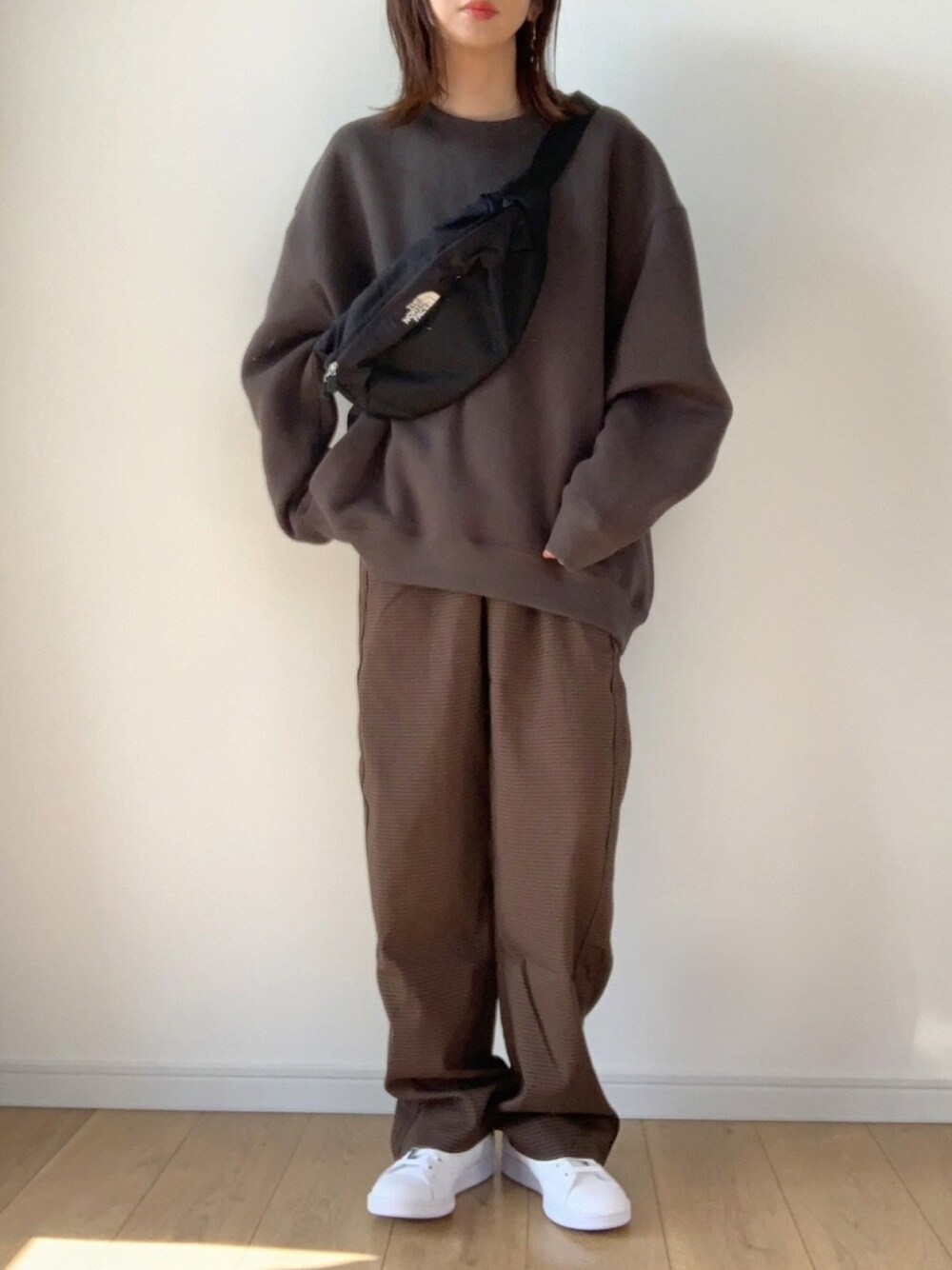 ブラウン系のその他パンツ、ホワイト系のスニーカー、ブラック系のボディバッグ/ウエストポーチを着用したレディースの秋コーディネートの1枚目の写真