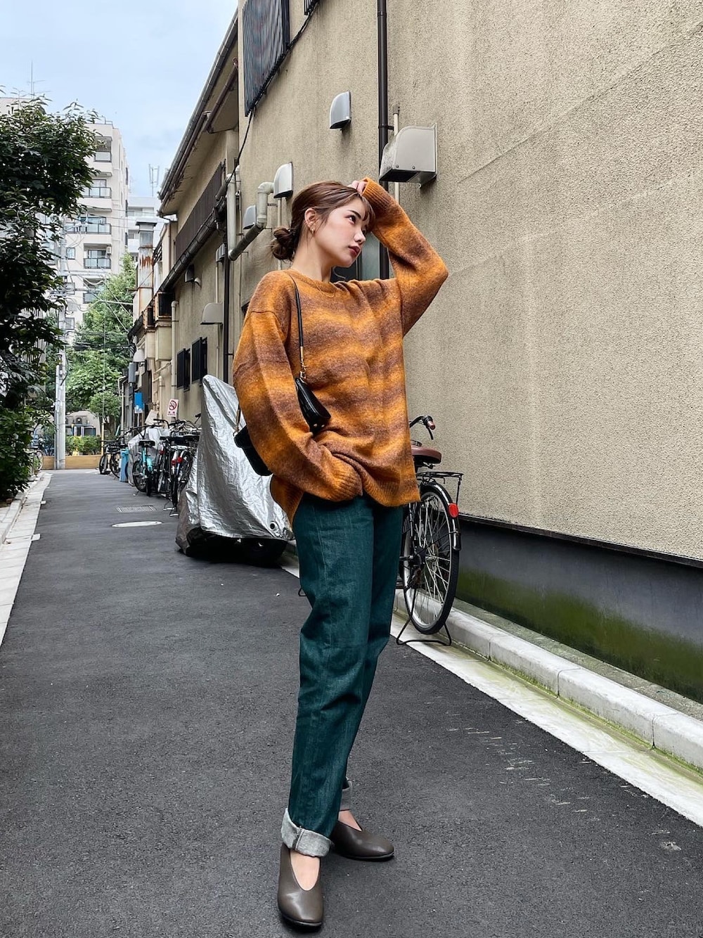 オレンジ系のニット/セーター、グリーン系のデニムパンツ、ブラック系のボストンバッグを着用したレディースの秋コーディネートの1枚目の写真