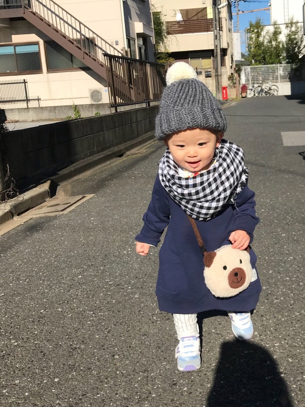 ブルー系のワンピース、パープル系のスニーカー、ブラウン系のバッグを着用したキッズの秋コーディネートの1枚目の写真