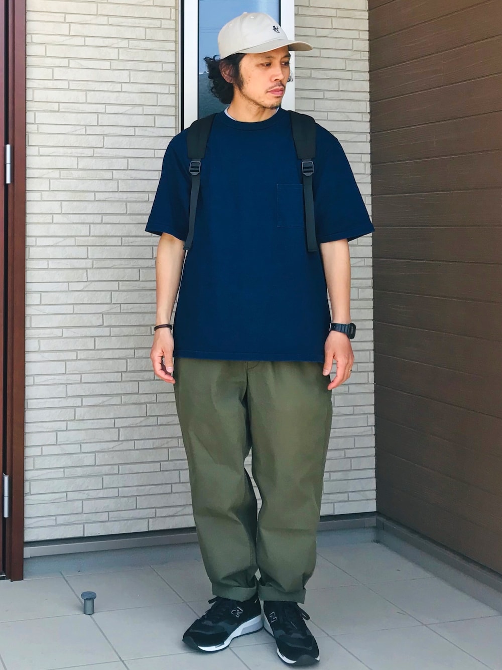 「ロゴキャップ、ベージュ、Tシャツ、インディゴ、バックパック、リュック、黒リュック、テーパードパンツ、カーキ、黒スニーカー」｜「nanamicaのアイテム（キャップ、ベージュ系）」を使った、ガッツ‘石ころ’松さん（メンズ・170cm）の春コーディネートの1枚目の写真