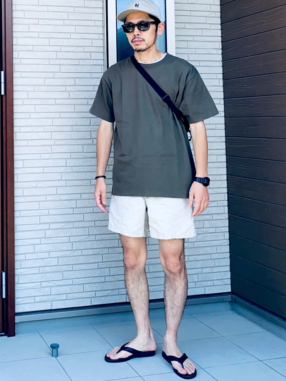 グリーン系のTシャツ/カットソー、ベージュ系のパンツ、ブラック系のサンダルを着用したメンズの夏コーディネートの1枚目の写真