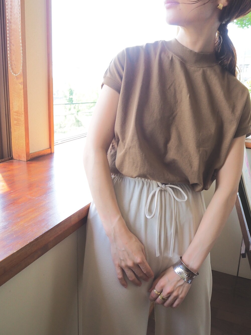 ブラウン系のTシャツ/カットソー、ベージュ系のその他パンツ、その他のバングル/リストバンドを着用したレディースの春コーディネートの1枚目の写真