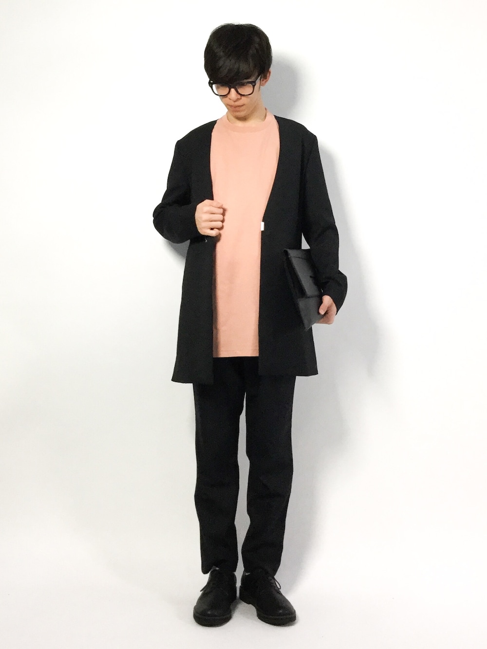 ブラック系のチェスターコート、ピンク系のTシャツ/カットソー、ブラック系のその他パンツを着用したメンズの春コーディネートの1枚目の写真