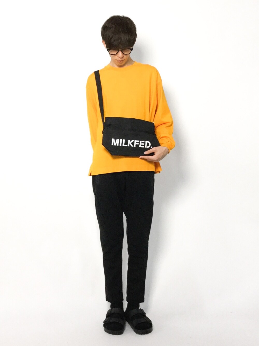 オレンジ系のTシャツ/カットソー、ブラック系のショルダーバッグ、ブラック系のスウェットパンツを着用したメンズの夏コーディネートの1枚目の写真