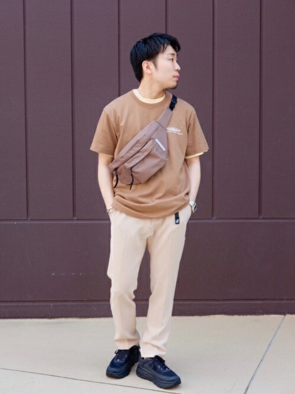 ベージュ系のTシャツ/カットソー、ベージュ系のスラックス、ベージュ系のボディバッグ/ウエストポーチを着用したメンズの春コーディネートの1枚目の写真