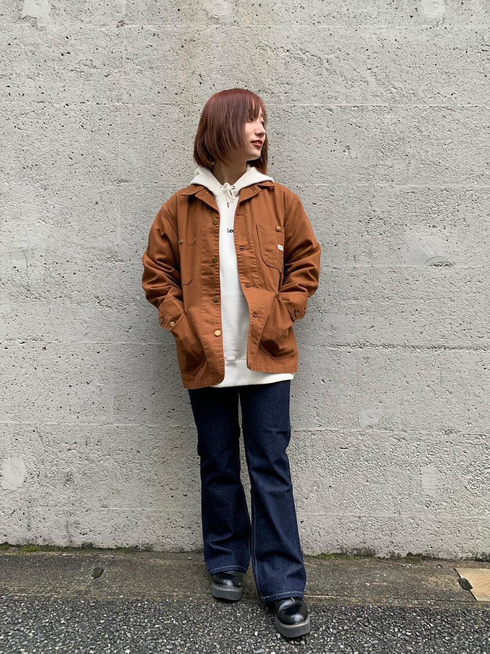 ブラウン系のカバーオール、ホワイト系のパーカー、ブルー系のデニムパンツを着用したレディースの冬コーディネートの1枚目の写真