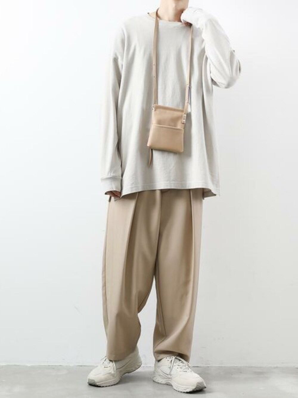 ホワイト系のTシャツ/カットソー、ベージュ系のスラックス、ベージュ系のショルダーバッグを着用したメンズの冬コーディネートの1枚目の写真