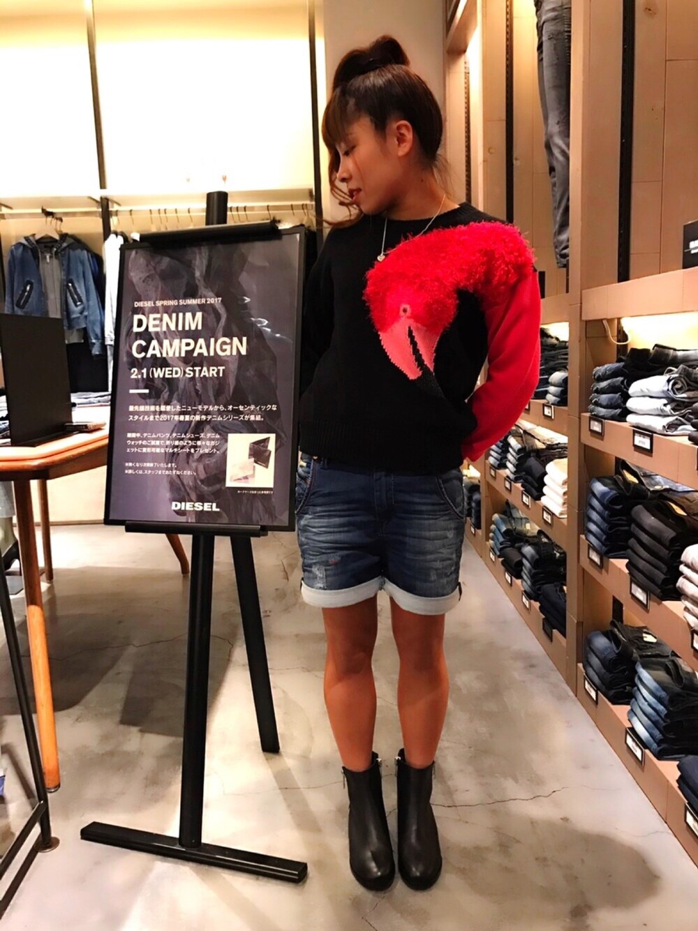 ブラック系のニット/セーター、ブルー系のデニムパンツ、ブラック系のブーツを着用したレディースの冬コーディネートの1枚目の写真