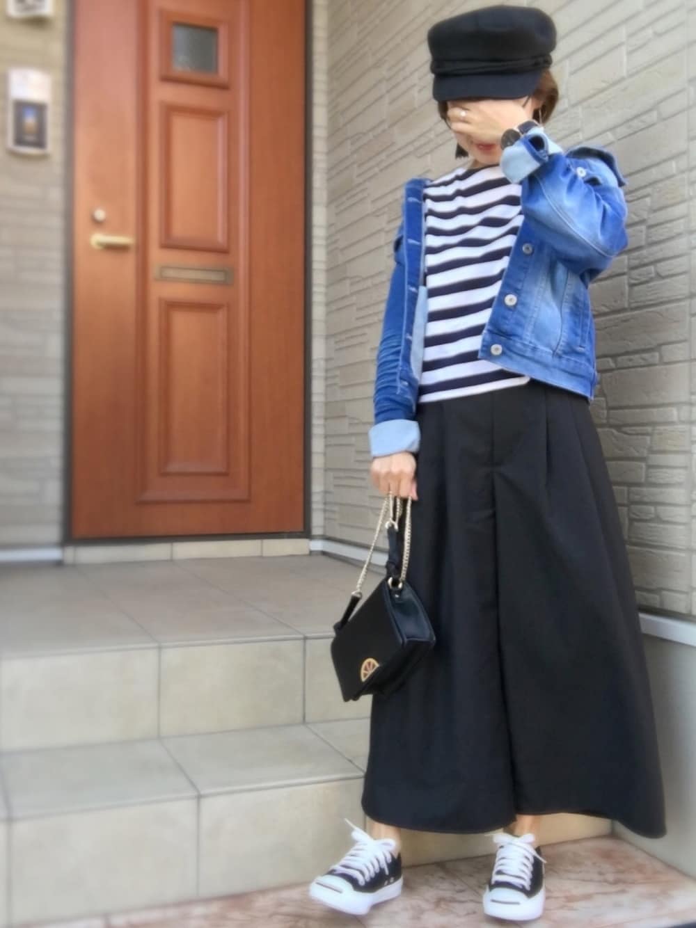 ブルー系のデニムジャケット、ブラック系のスニーカー、ブラック系のキャスケットを着用したレディースの秋コーディネートの1枚目の写真