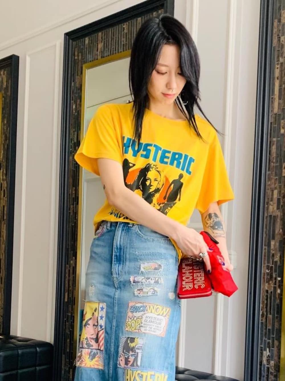 ブルー系のデニムスカート、イエロー系のTシャツ/カットソー、レッド系の財布を着用したレディースの夏コーディネートの1枚目の写真