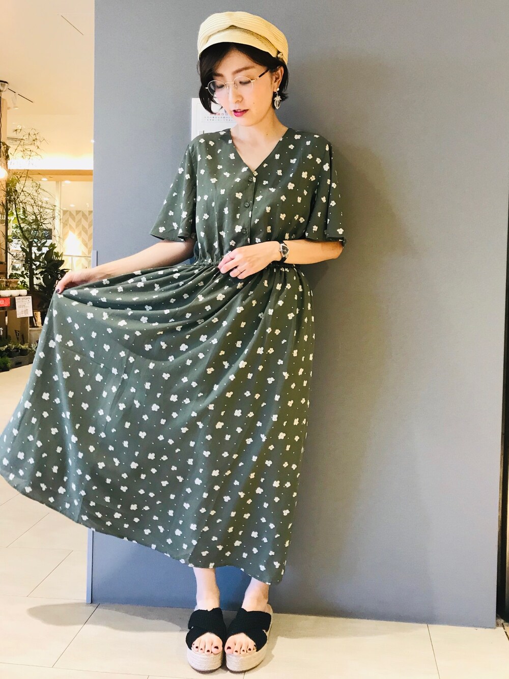 グリーン系のワンピース、ホワイト系のサンダル、ベージュ系のキャップを着用したレディースの夏コーディネートの1枚目の写真