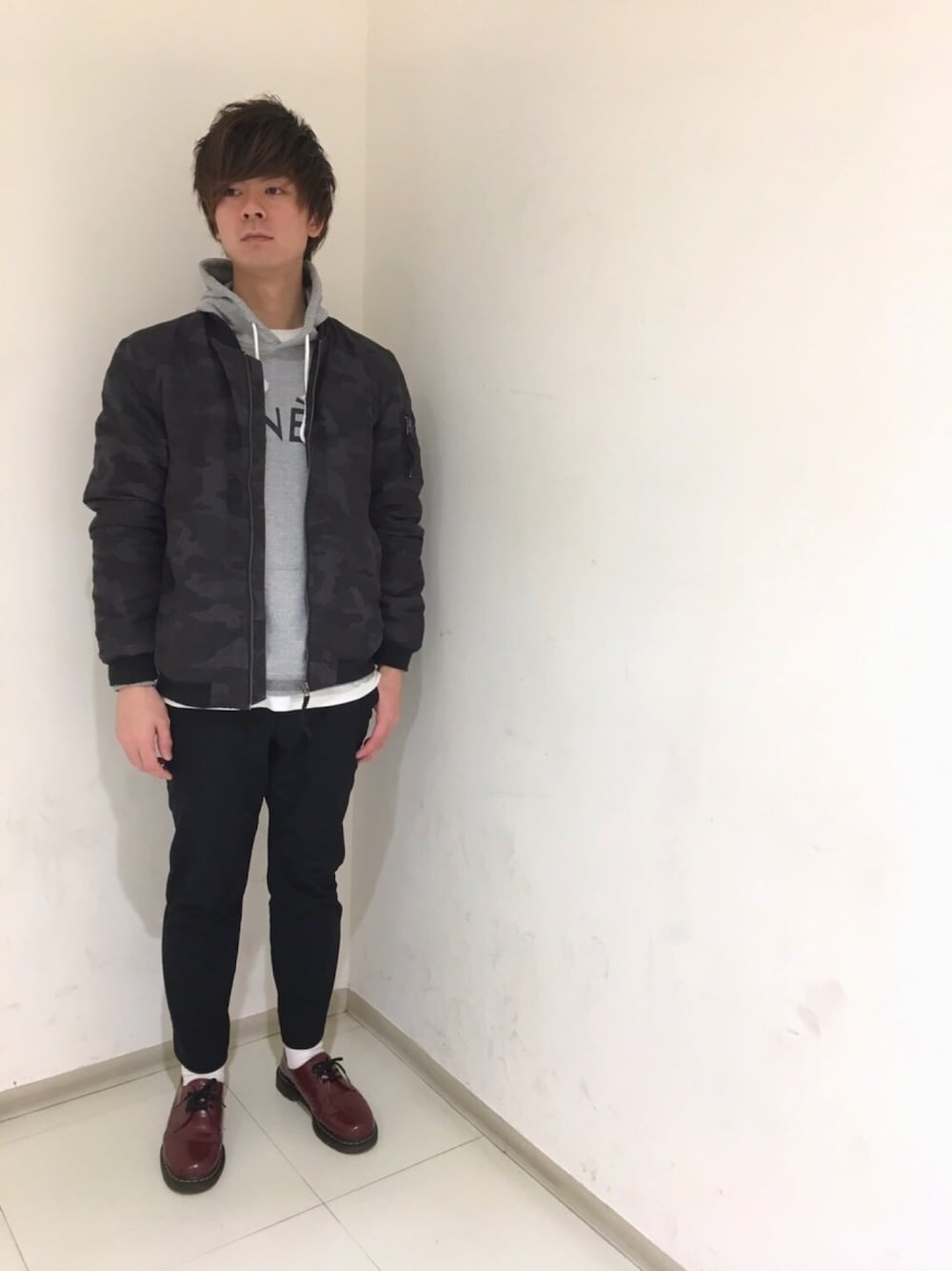 ブラック系のミリタリージャケット、グレー系のパーカー、ホワイト系のTシャツ/カットソーを着用したメンズの春コーディネートの1枚目の写真