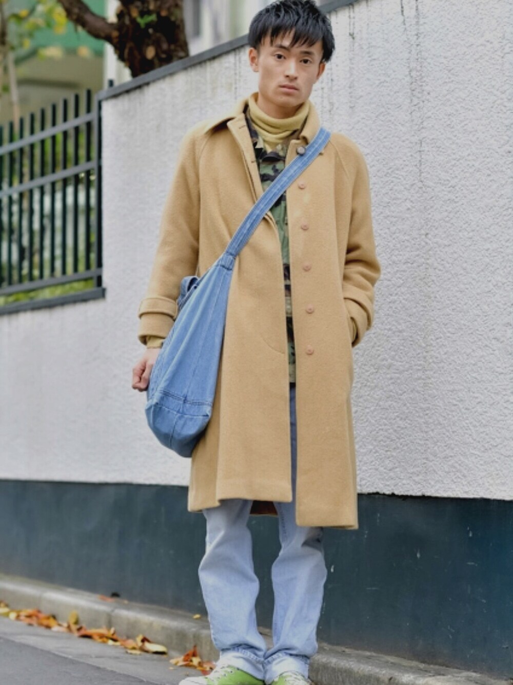 ベージュ系のチェスターコート、ブルー系のデニムパンツ、ベージュ系のニット/セーターを着用したメンズの冬コーディネートの1枚目の写真