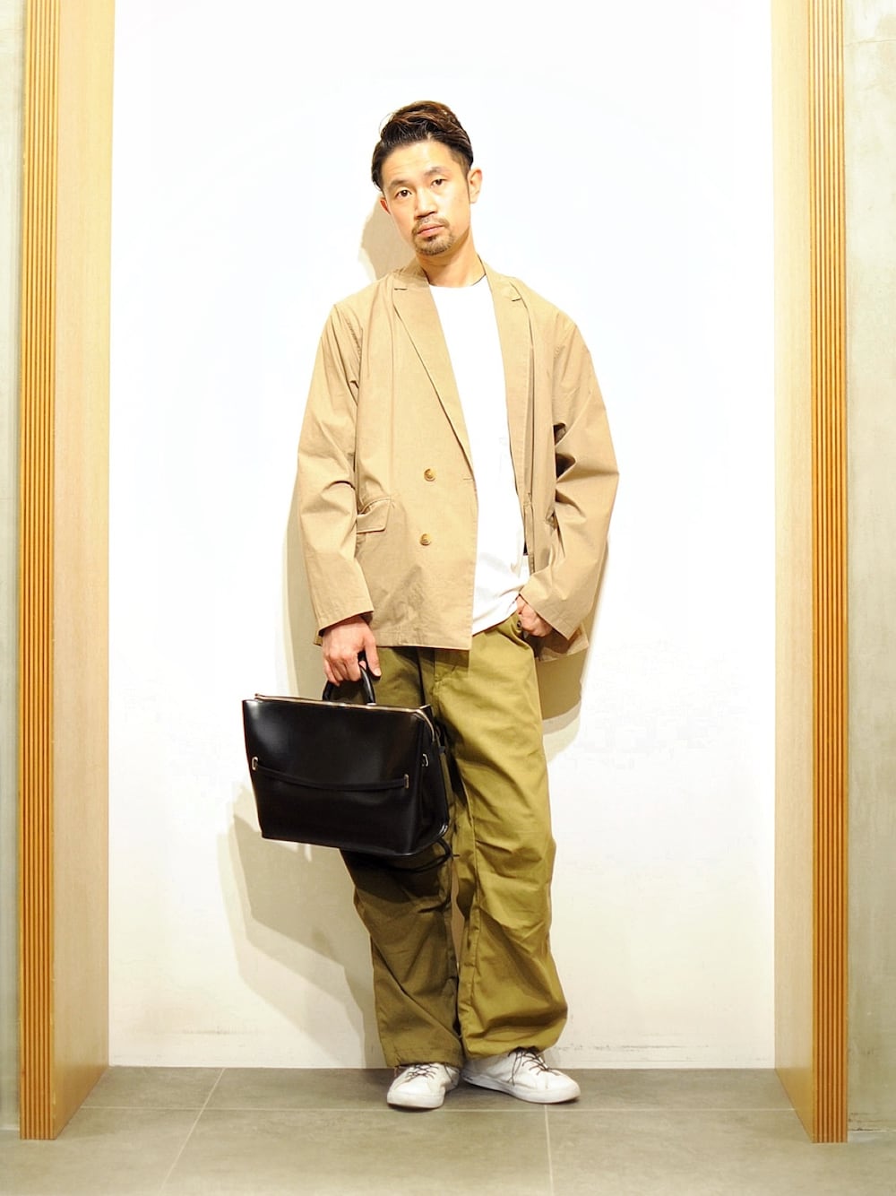 グリーン系のパンツ、ベージュ系のテーラードジャケット、ホワイト系のTシャツ/カットソーを着用したメンズの春コーディネートの1枚目の写真