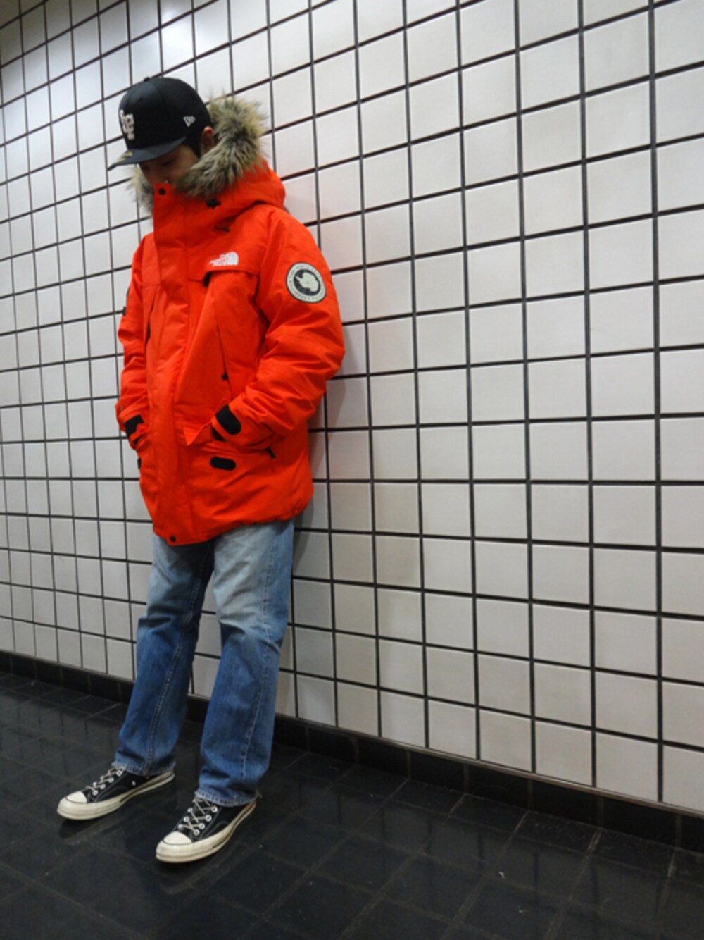 オレンジ系のマウンテンパーカーを着用したメンズの冬コーディネートの1枚目の写真