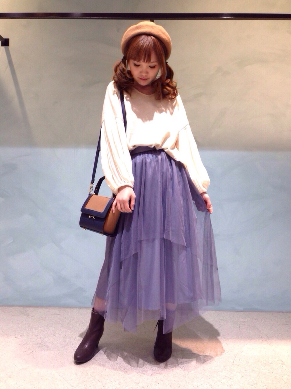 ブラウン系のブーツ、ブルー系のショルダーバッグ、ベージュ系のニット/セーターを着用したレディースの冬コーディネートの1枚目の写真