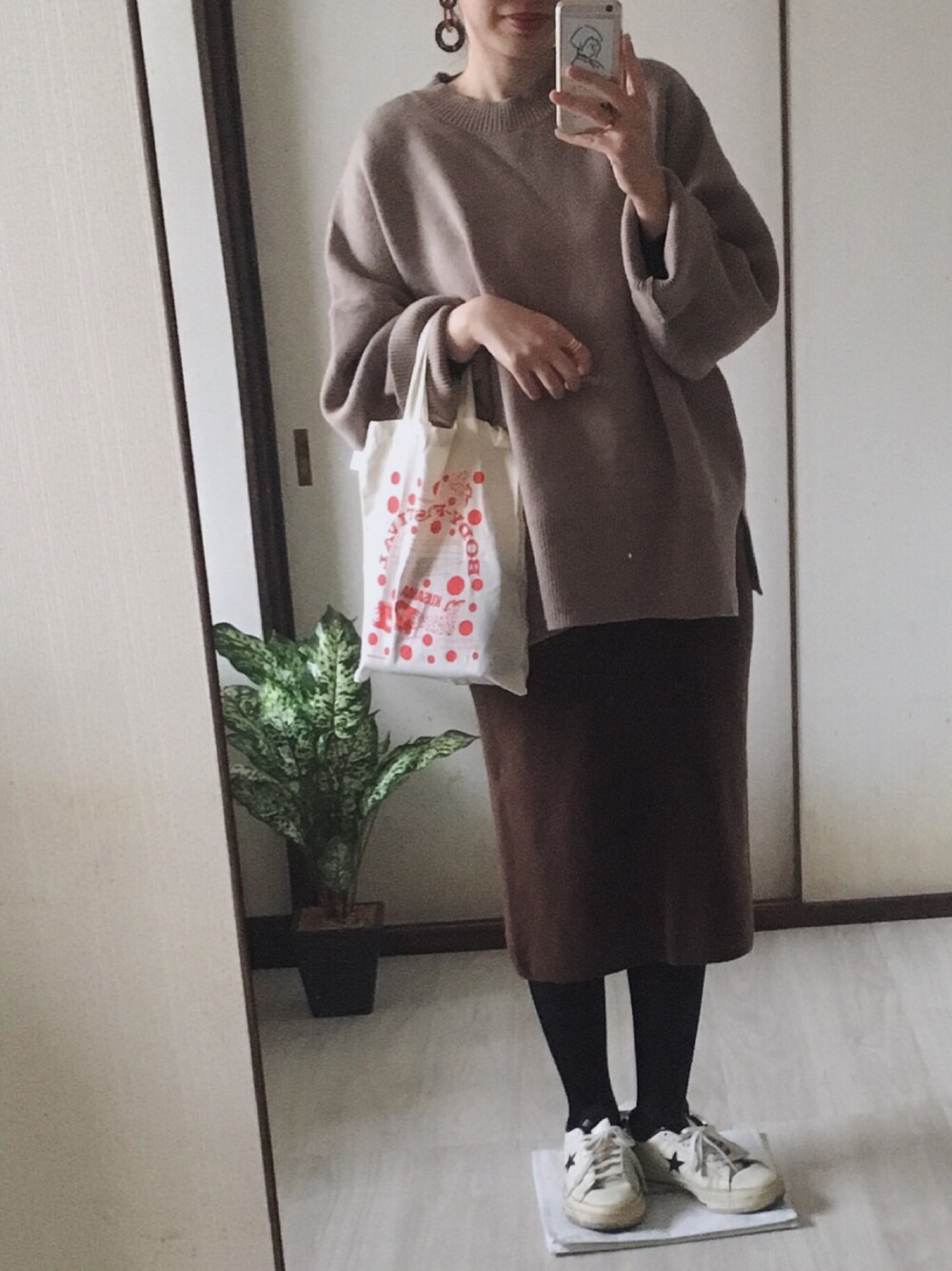 ベージュ系のニット/セーター、ホワイト系のスニーカー、ベージュ系のノーカラーコートを着用したレディースの冬コーディネートの1枚目の写真