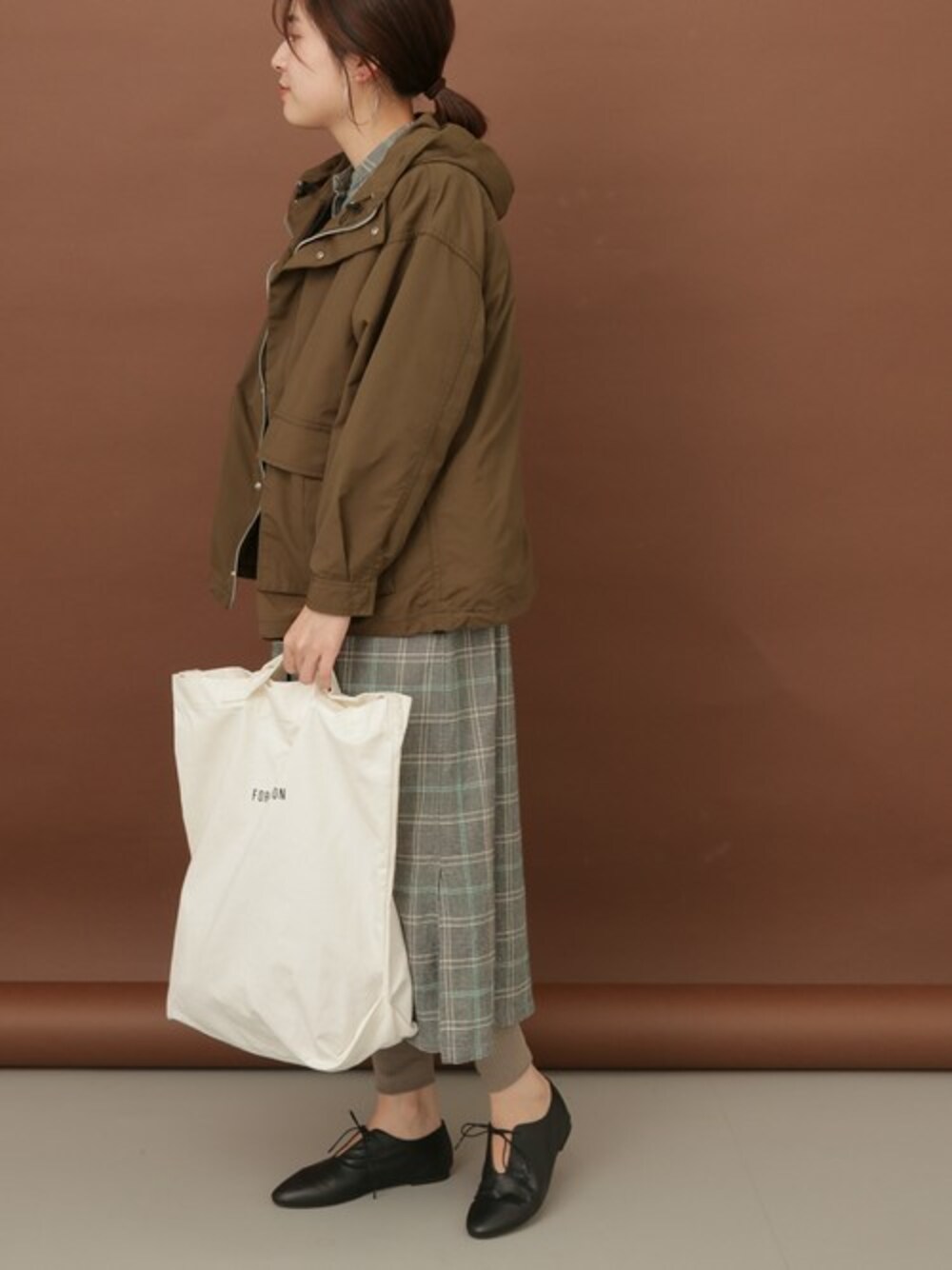 グリーン系のワンピース、グリーン系のマウンテンパーカー、ホワイト系のトートバッグを着用したレディースの秋コーディネートの1枚目の写真