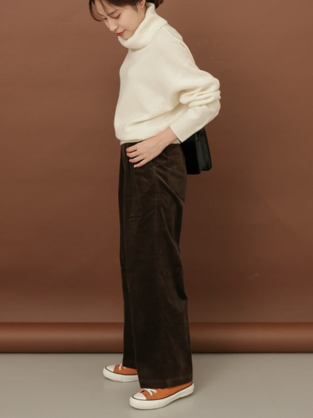 ホワイト系のニット/セーター、ブラウン系のその他パンツ、オレンジ系のスニーカーを着用したレディースの秋コーディネートの1枚目の写真