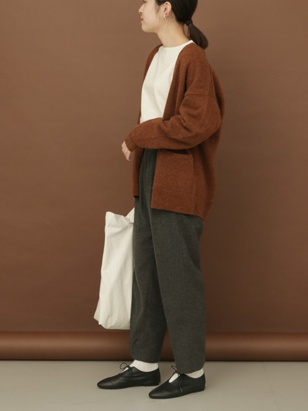 ブラウン系のカーディガン/ボレロ、ホワイト系のTシャツ/カットソー、グレー系のその他パンツを着用したレディースの秋コーディネートの1枚目の写真