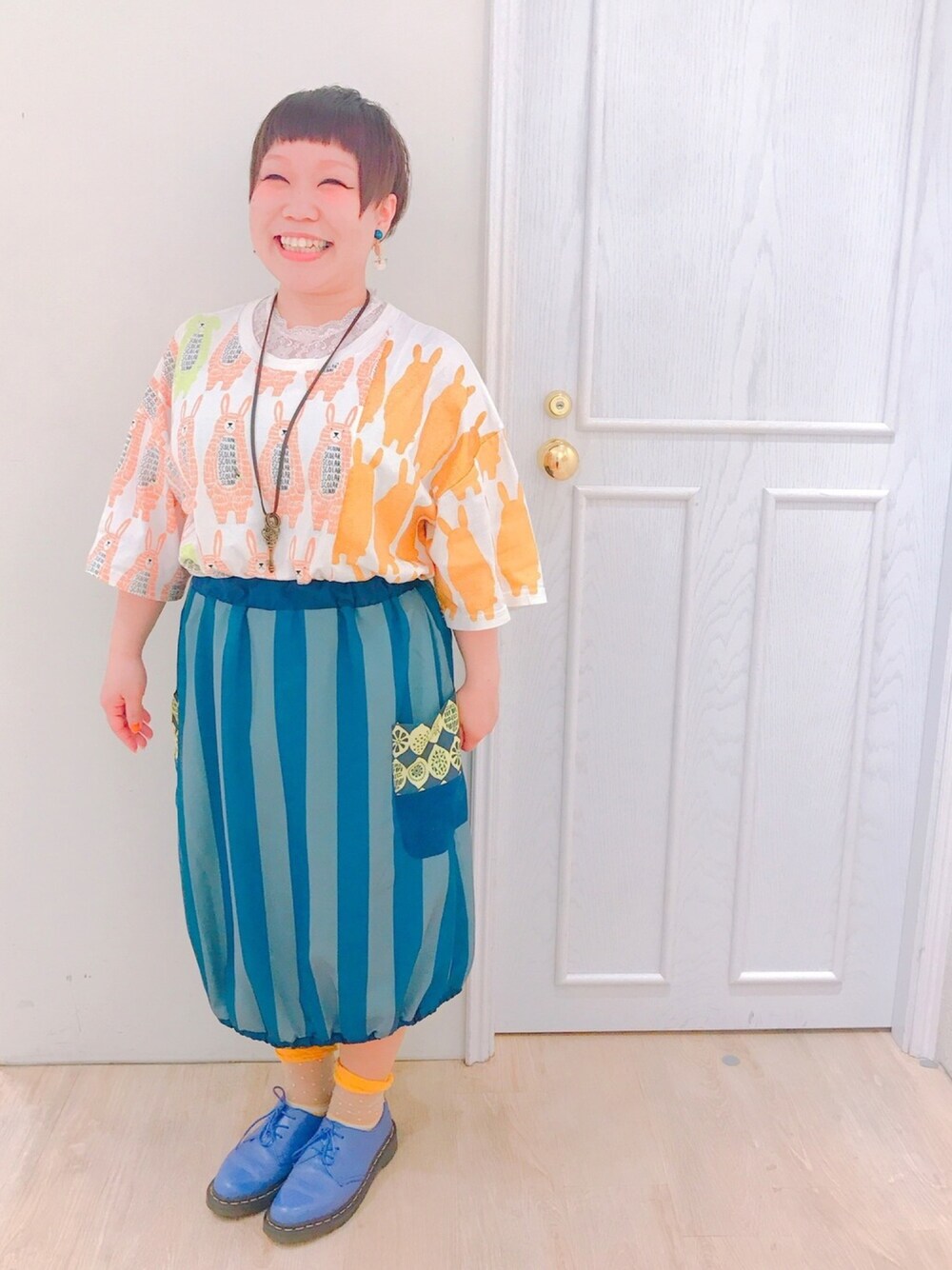 ホワイト系のワンピース、パープル系のシューズ、ブルー系のスカートを着用したレディースの春コーディネートの1枚目の写真