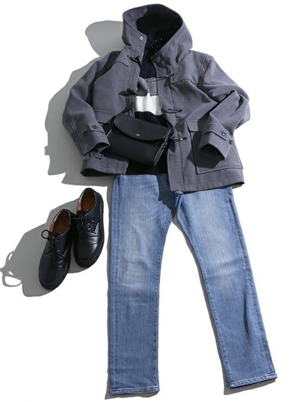 グレー系のダッフルコート、ブルー系のニット/セーター、ブルー系のデニムパンツを着用したメンズの冬コーディネートの1枚目の写真