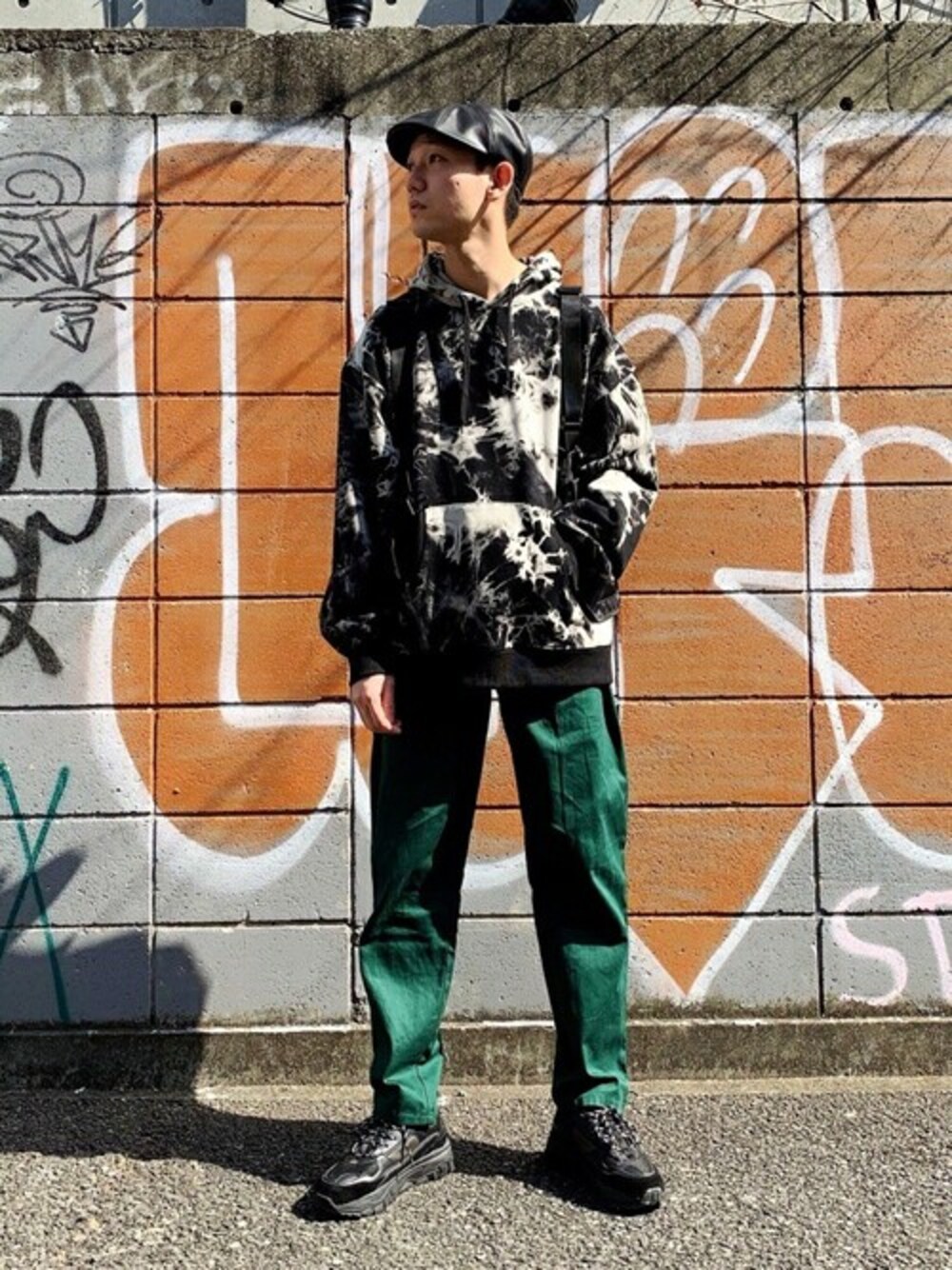 ブラック系のスニーカー、グリーン系のチノパンツ、ブラック系のハンチング/ベレー帽を着用したメンズの夏コーディネートの1枚目の写真