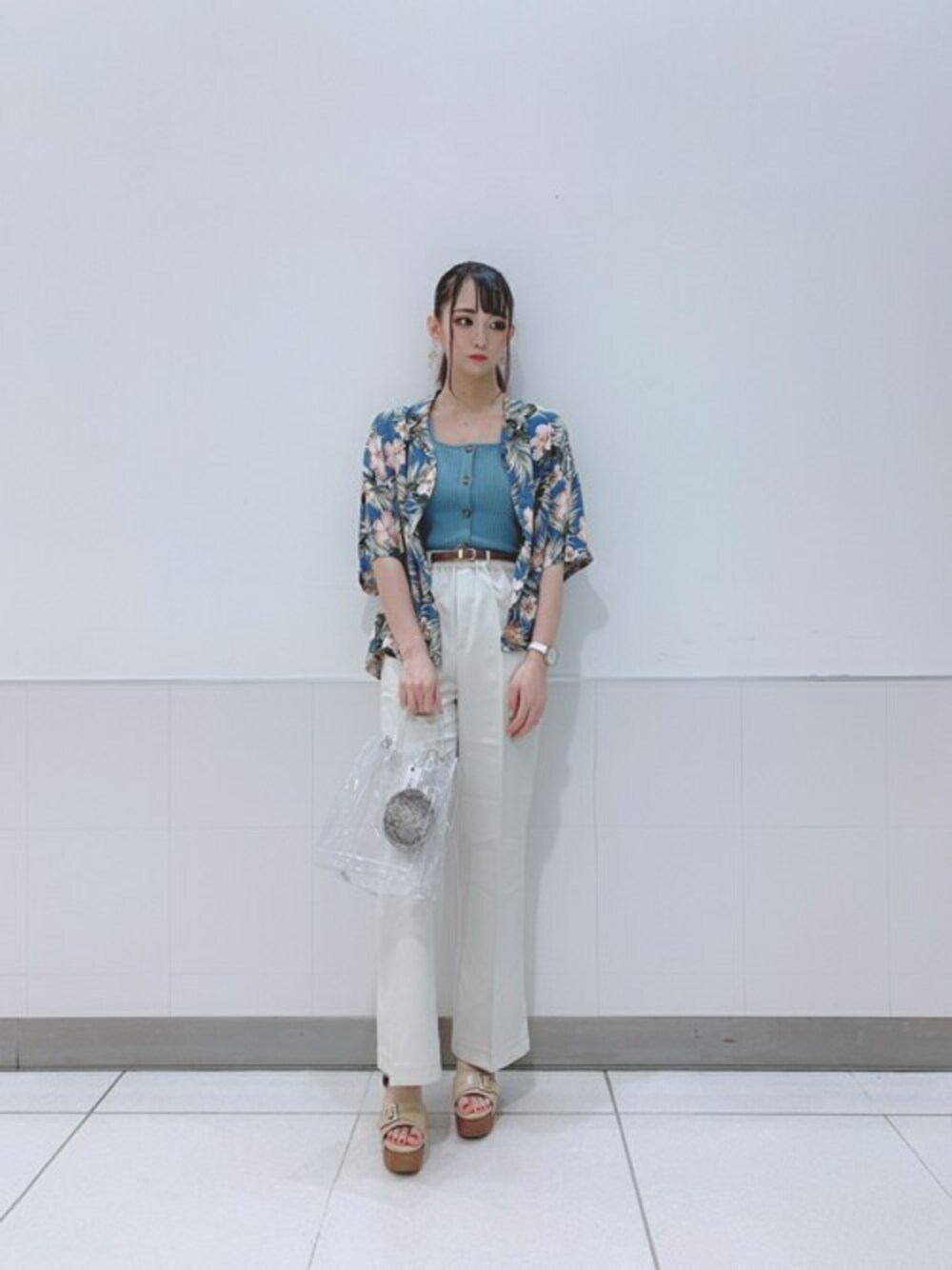 ホワイト系のショルダーバッグ、ブルー系のタンクトップ、ホワイト系のスラックスを着用したレディースの夏コーディネートの1枚目の写真