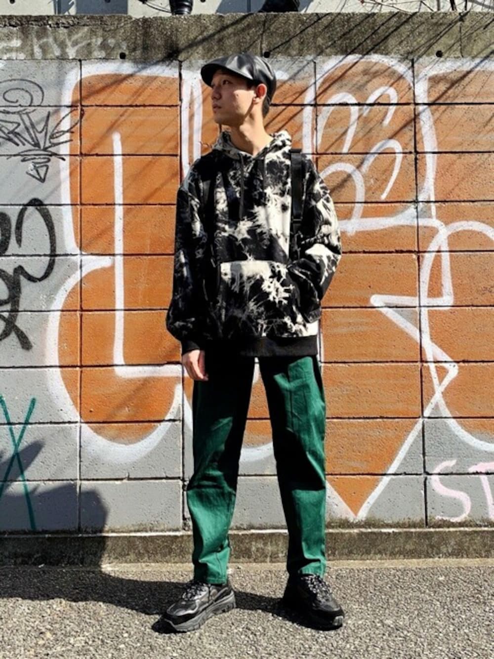 グリーン系のチノパンツ、ブラック系のスニーカー、ブラック系のハンチング/ベレー帽を着用したメンズの秋コーディネートの1枚目の写真