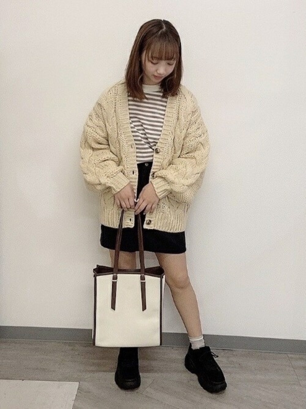 ブラック系のスカート、ベージュ系のカーディガン/ボレロ、ベージュ系のTシャツ/カットソーを着用したレディースの秋コーディネートの1枚目の写真