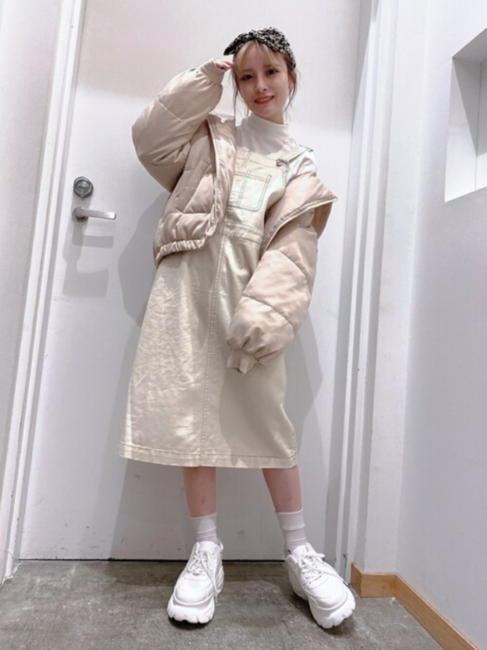 ホワイト系のTシャツ/カットソー、ベージュ系のダウンジャケット/コート、ホワイト系のジャンパースカートを着用したレディースの秋コーディネートの1枚目の写真