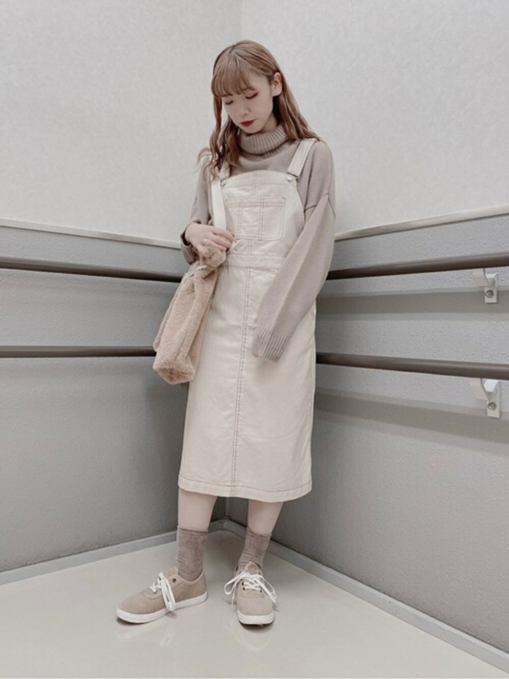 ブラウン系のニット/セーター、ホワイト系のジャンパースカート、ベージュ系のトートバッグを着用したレディースの秋コーディネートの1枚目の写真
