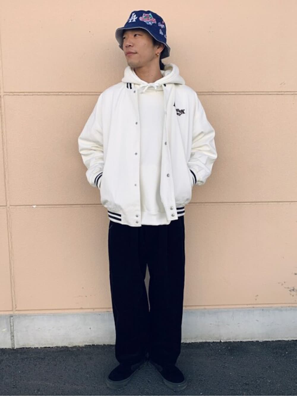 ホワイト系のスタジャン、ホワイト系のパーカー、ブラック系のスラックスを着用したメンズの秋コーディネートの1枚目の写真