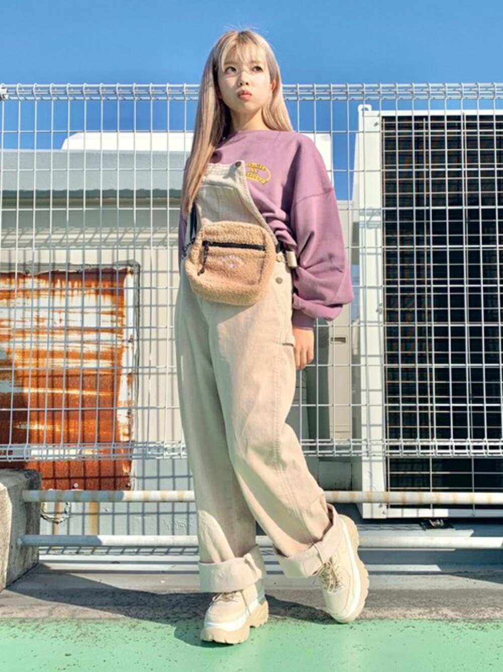 ホワイト系のサロペット/オーバーオール、パープル系のスウェット、ベージュ系のスニーカーを着用したレディースの秋コーディネートの1枚目の写真