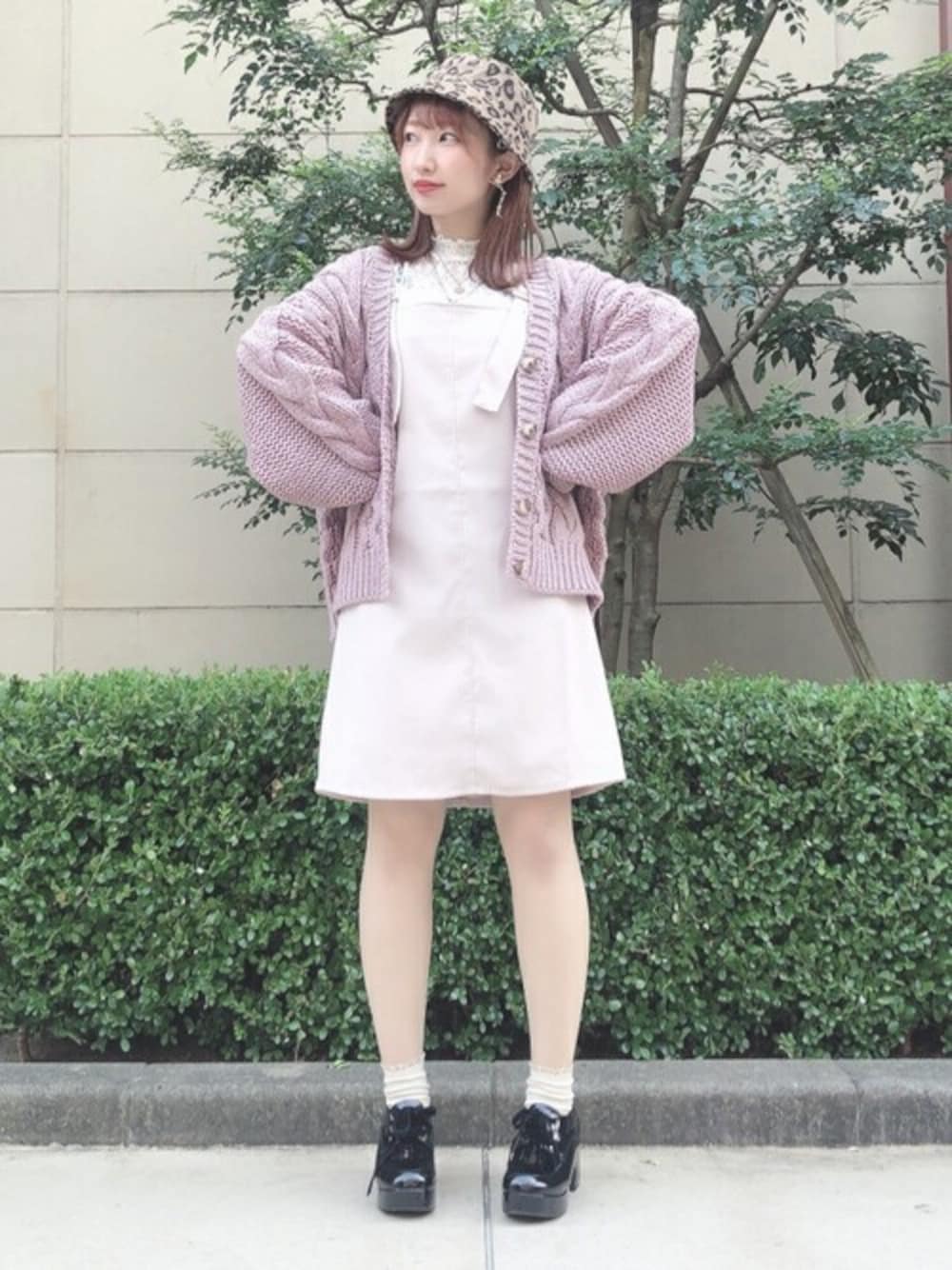 ピンク系のカーディガン/ボレロ、ホワイト系のシャツ/ブラウス、ホワイト系のジャンパースカートを着用したレディースの秋コーディネートの1枚目の写真
