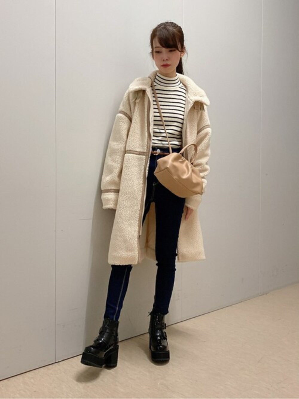 ホワイト系のニット/セーター、ブルー系のデニムパンツ、ベージュ系のショルダーバッグを着用したレディースの秋コーディネートの1枚目の写真
