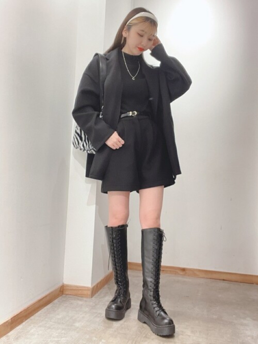 ブラック系のテーラードジャケット、その他のショルダーバッグ、ブラック系のブーツを着用したレディースの冬コーディネートの1枚目の写真