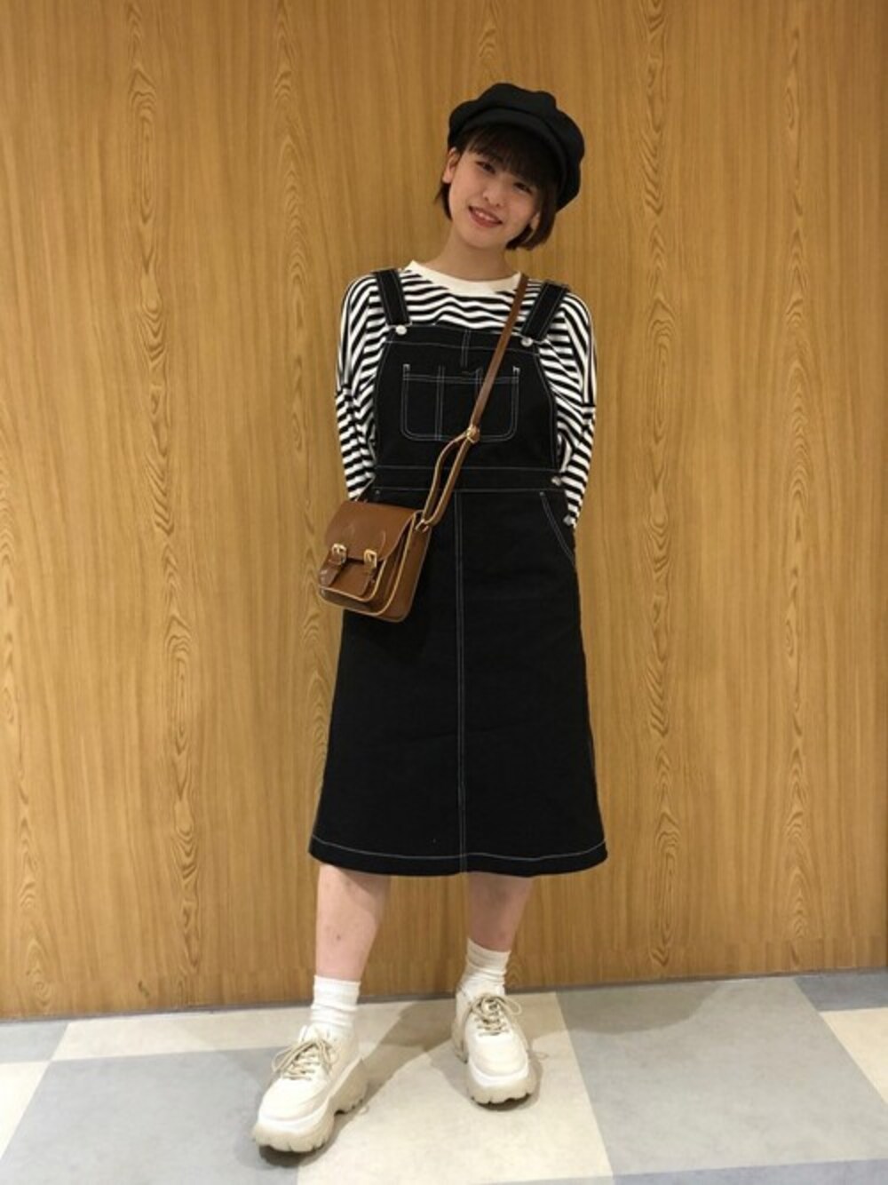 ブラック系のスウェット、ブラック系のジャンパースカート、ベージュ系のスニーカーを着用したレディースの冬コーディネートの1枚目の写真