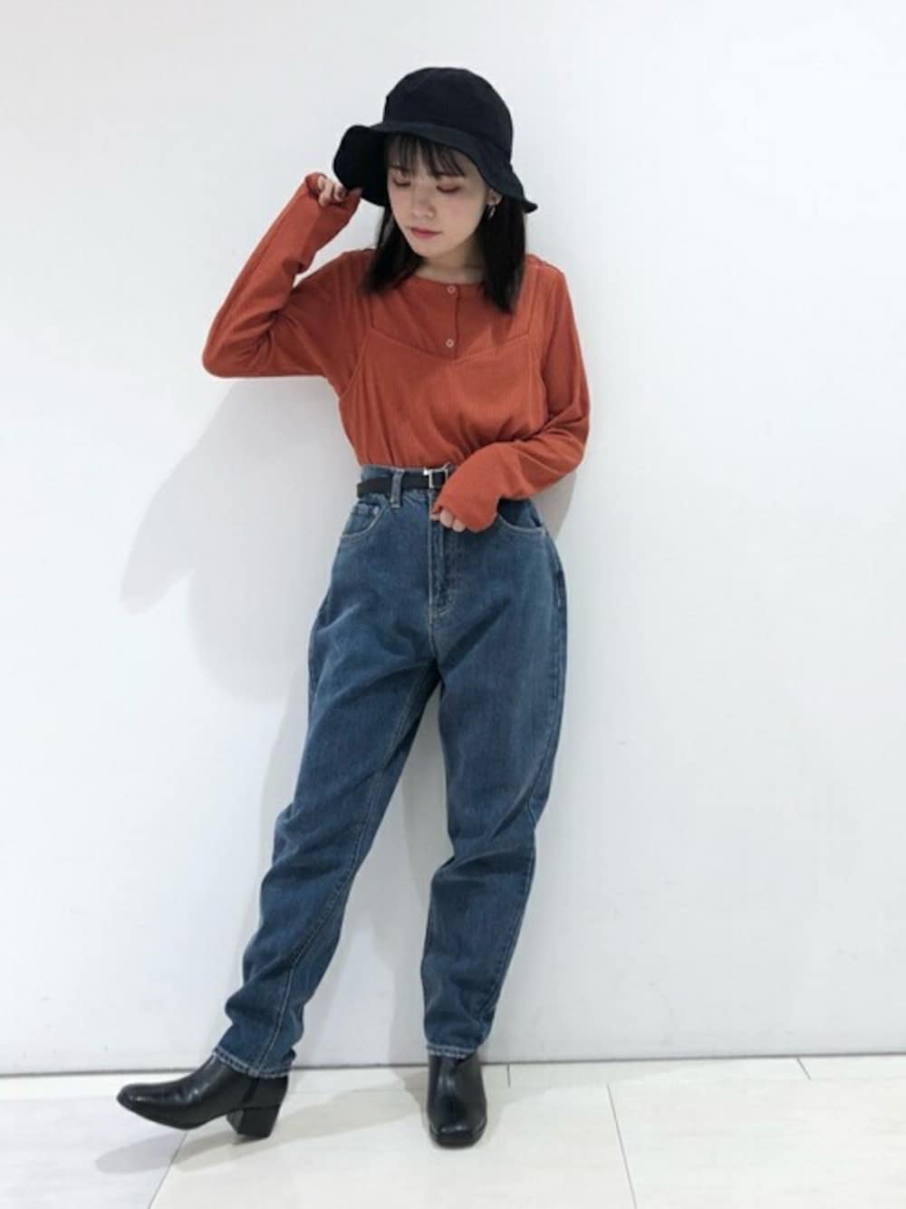 オレンジ系のTシャツ/カットソー、ブルー系のデニムパンツ、ブラック系のブーツを着用したレディースの冬コーディネートの1枚目の写真