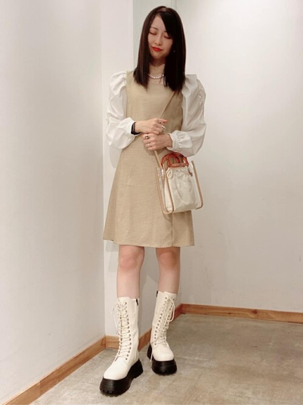ベージュ系のワンピース、ホワイト系のブーツ、ベージュ系のショルダーバッグを着用したレディースの春コーディネートの1枚目の写真