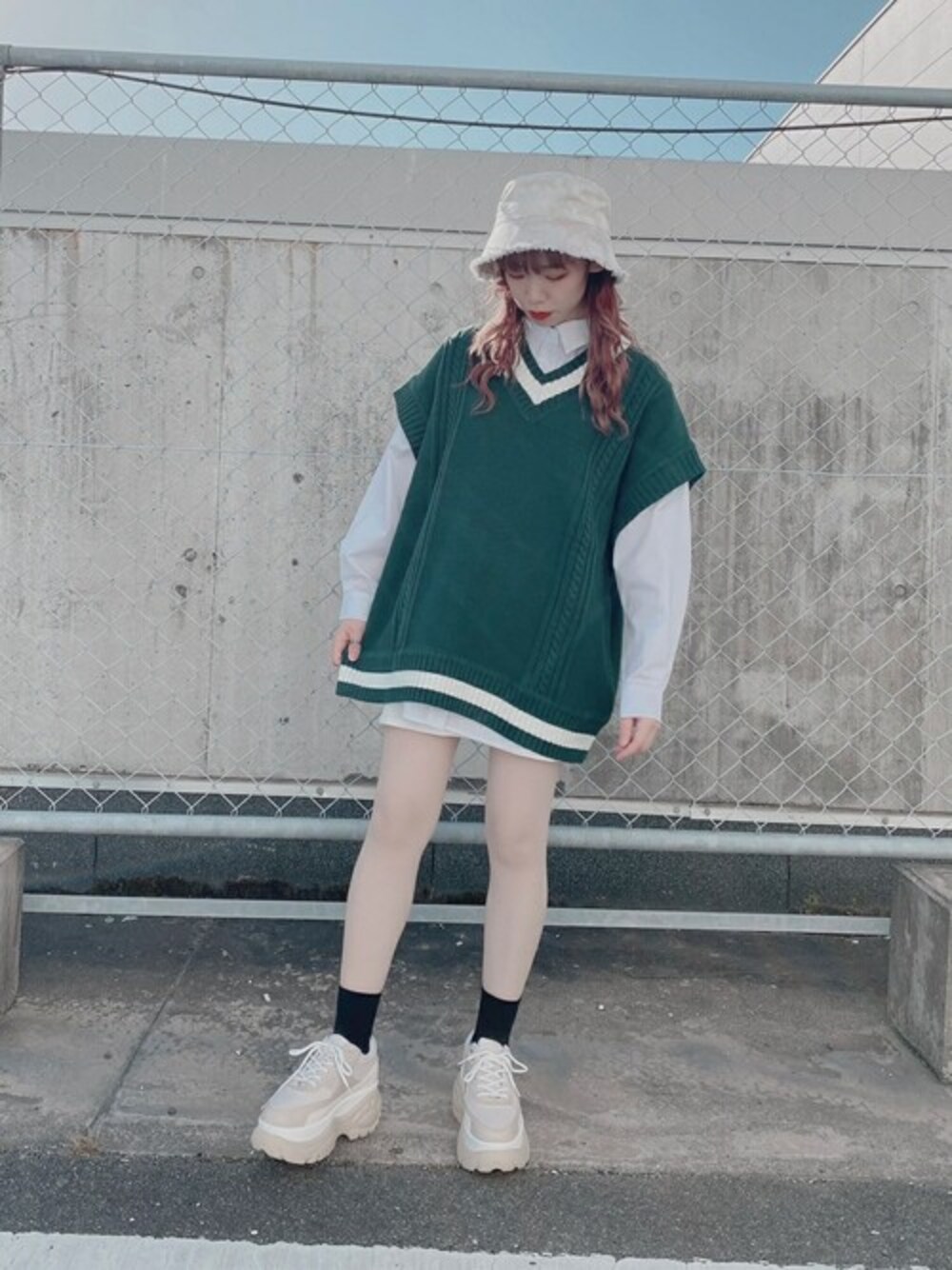 ホワイト系のシャツ/ブラウス、グリーン系のベスト、ベージュ系のスニーカーを着用したレディースの春コーディネートの1枚目の写真