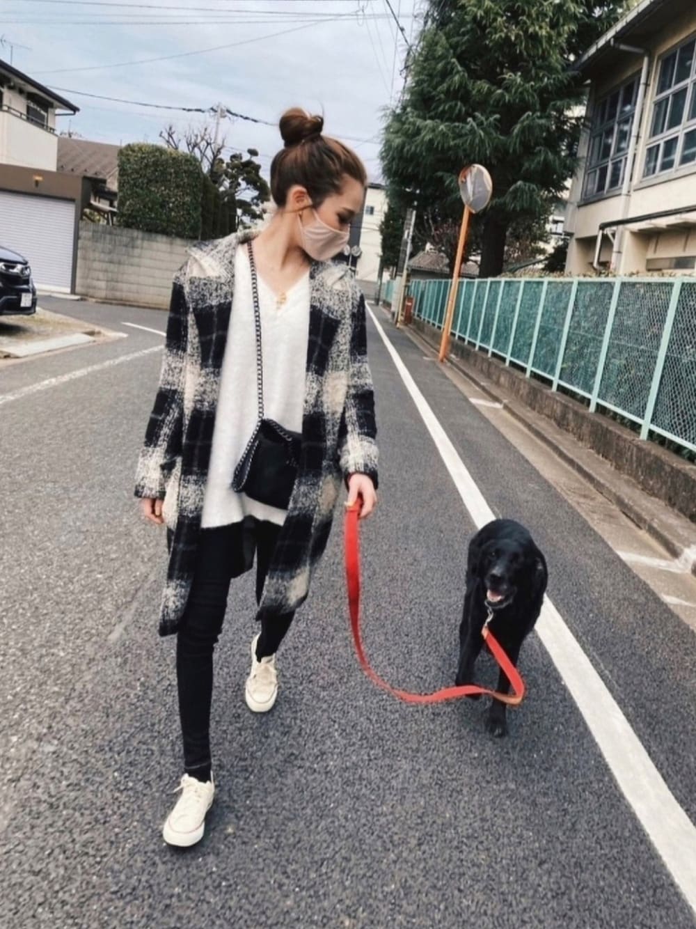 ブラック系のチェスターコート、ブラック系のデニムパンツ、ベージュ系のスニーカーを着用したレディースの春コーディネートの1枚目の写真